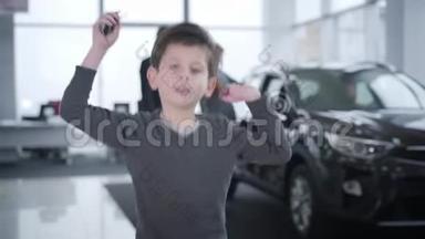 一幅快乐的小白种人男孩拿着车钥匙在展厅里跳跃的肖像。 站在车旁边的父母